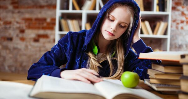 Woman Wearing Blue Jacket Sitting on Chair Near Table Reading Books